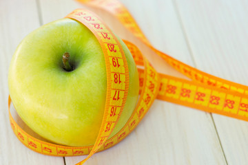 Dieting concept. Green apple with measuring tape. Green apples measured the meter, sports apple