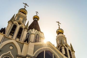 Russian Orthodox Church towers with three domes and crosses at sunbeam low sun