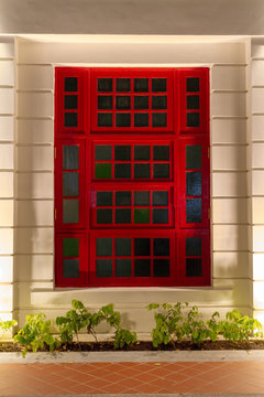 A Red Window Frame On A White Building At Night.