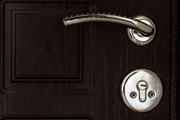 Steel door with dark brown texture. Door knob and key lock close-up.