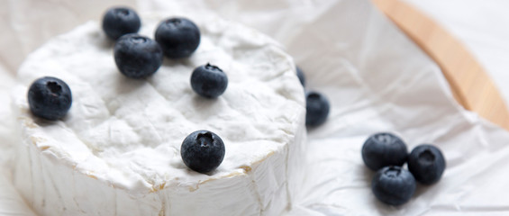 Camembert cheese with blueberries on bamboo board, closeup. Food for wine.