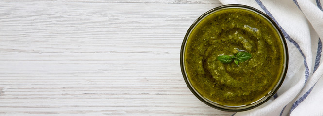 Basil pesto on white wooden surface, overhead view. Space for text.