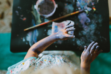 Portrait of adorable baby girl drawing with paints at home