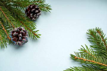 Obraz na płótnie Canvas Frame Christmas decoration with fir branches, pine cones and shiny, blue background,copy space.