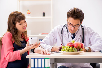 Pregnant woman visiting doctor discussing healthy diet