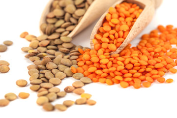 dry brown and yellow lentils on wooden spoon isolated on a white background