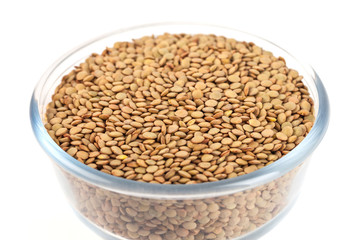 Dry lentil in glass bowl isolated on white background
