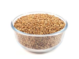 Dry lentil in glass bowl isolated on white background