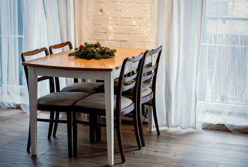 View on a Christmas tree branch decoration on table with chairs on a kitchen.