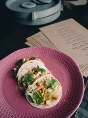 Tacos with chicken and crumbs on pink plate