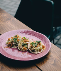 Tacos with chicken and crumbs on pink plate