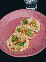 Tacos with chicken and crumbs on pink plate