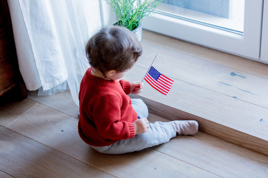 Little baby boy with USA flagg sitting on a floor at home