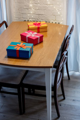 Colored gift boxes on table with Christmas lights on background