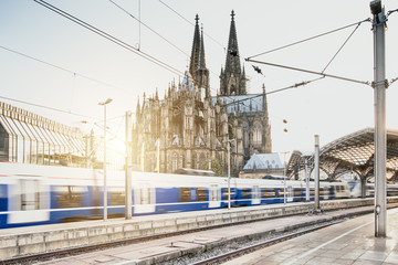 Schneller Zug fährt mit Kölner Dom im Hintergrund bei Sonnenuntergang