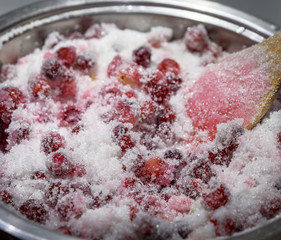 berries of ripe red cranberries with sugar in an iron pan