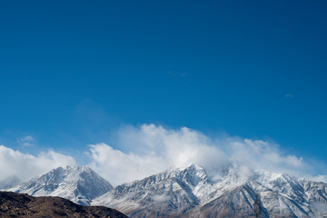 Obraz premium clouds and fresh fallen show on Eastern Sierra Nevadas, California, USA 