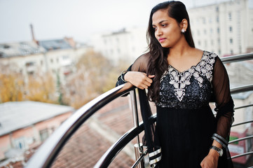 Pretty indian girl in black saree dress posed at balkony.