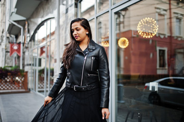 Fototapeta premium Pretty indian girl in black saree dress and leather jacket posed outdoor at street.