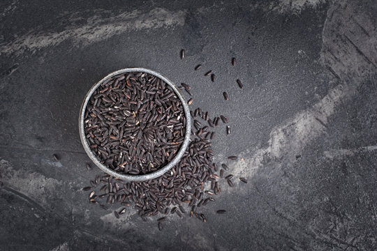Top view of uncooked black rice in gray bowl