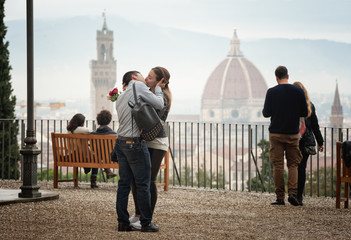 Young couple in love embracing and kissing. Florence romantic cityscape panorama in the background.
