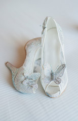 Fototapeta na wymiar white high heels with butterfly adornment, white sparkling bridal heels, butterfly heels, bridal shoes