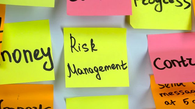 Hand glues a sticker with an inscription risk management on a board with stickers