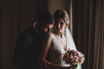 Wedding photo shoot of the newlyweds in a dark hotel room.