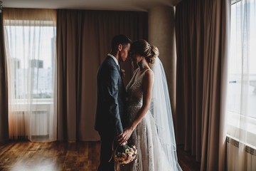 Wedding photo shoot of the newlyweds in a dark hotel room.