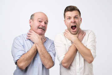 Two men showing choking gesture like they have problems with breathing.