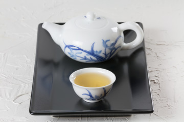 green japanese tea one white cup of tea and teapoton a black plate on a white background