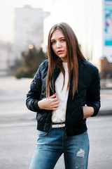fashion style portrait of young trendy girl posing along street