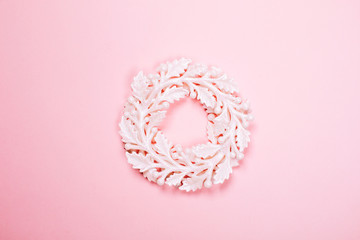Christmas decorative white wreath on pink pastel background. Macro. Festive concept.