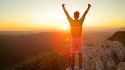 LENS FLARE: Male tourist celebrates reaching top of the mountain at sunrise.