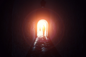 Light in end of tunnel with silhouettes of people, way to hope and freedom