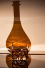 Gorgeous view of glass of alcohol drink with ice on shadow of bottle background. Beautiful backgrounds.