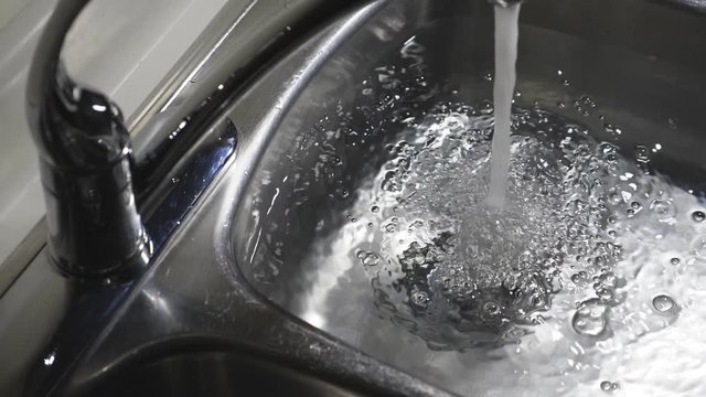 Slow motion kitchen sink filling with water. Dramatic and moody lighting.
