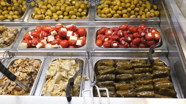 Delicous appetizers including dolmades and stuffed peppers at public market. Handheld, stabilized shot.