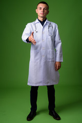 Young handsome man doctor against green background