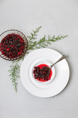 Homemade Cranberry Sauce on White Plate with Cedar Sprigs on a Light Gray Background