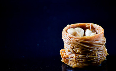 Middle Eastern dessert called mabroume or burma isolated on black background.