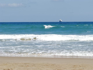 Ship on the horizon against the beach and clear sky