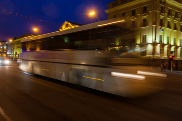 Naklejka premium The motion of a blurred bus on the avenue in the evening.