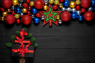 Christmas concept decoration with snow, new year gift boxes with red ribbon, xmas balls toys, fir branches, pine cone on  black wooden background with frame for promo text