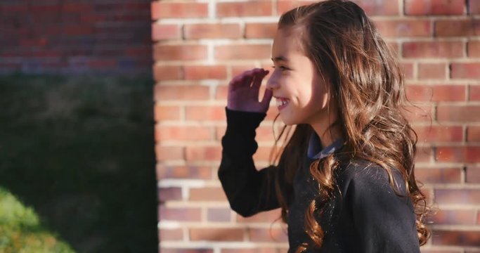 Little girl in front of a brick wall playing, pretending to be a fashion model