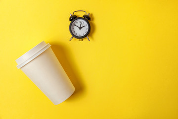 Simply flat lay design paper coffee cup and alarm clock on yellow colorful trendy background....