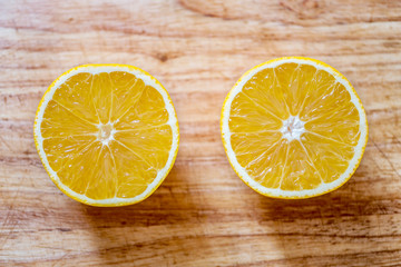 Two halves of a orange on a blurred wooden board