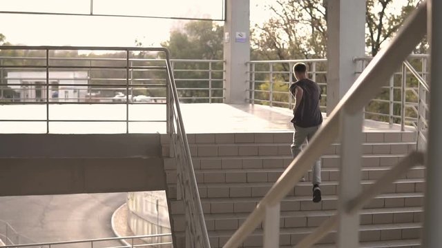 Young hooligan streetstyle guy running up by stairs on the football stadium at the evening at autumn