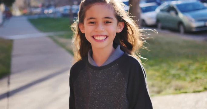 Little girl back-lit by the afternoon light is silly on the sidewalk