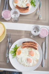 Traditional breakfast with  sausages, fried eggs, bread and yogurt
